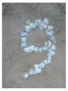 Dibuix d'un número 9 sobre la sorra de la platja